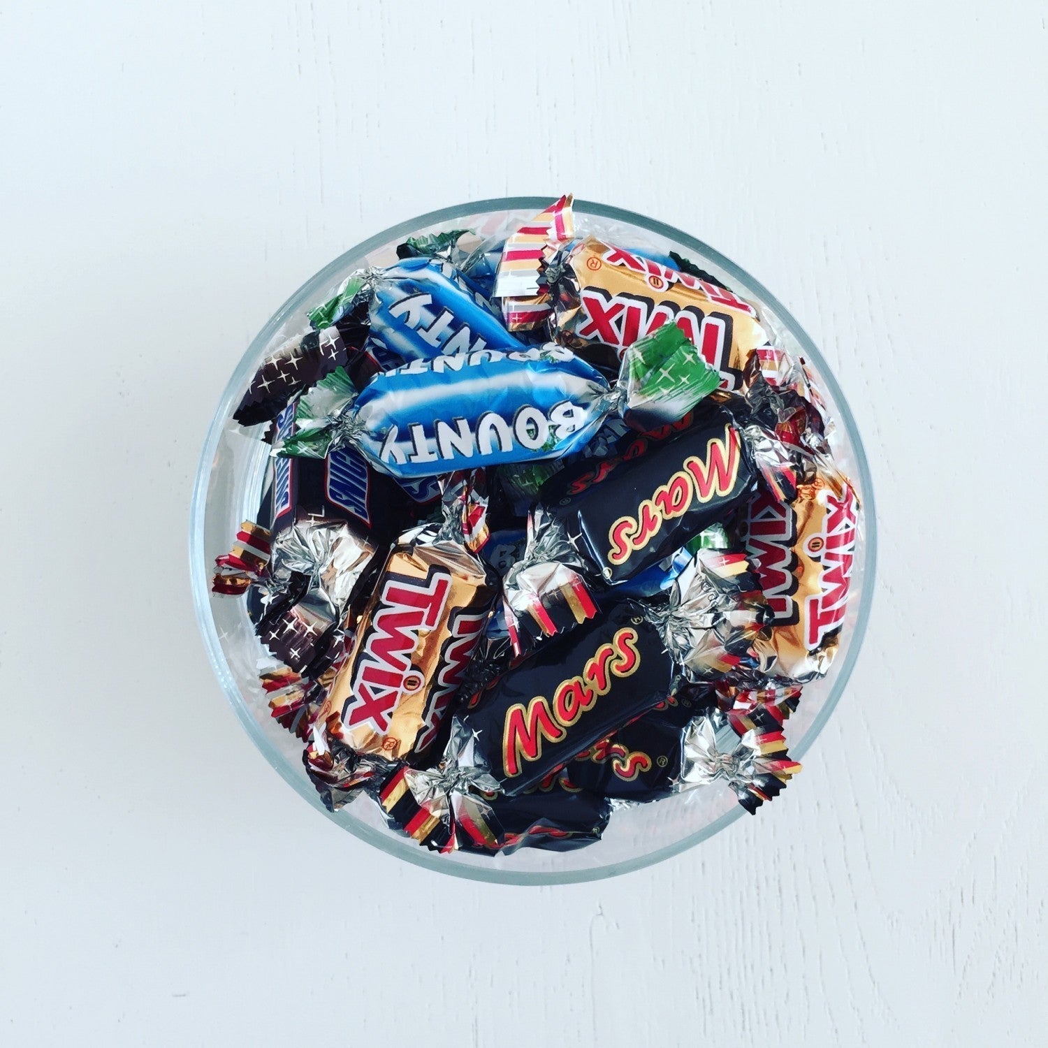 Skål med små chokoladebarer pakket ind i farverigt slikpapir